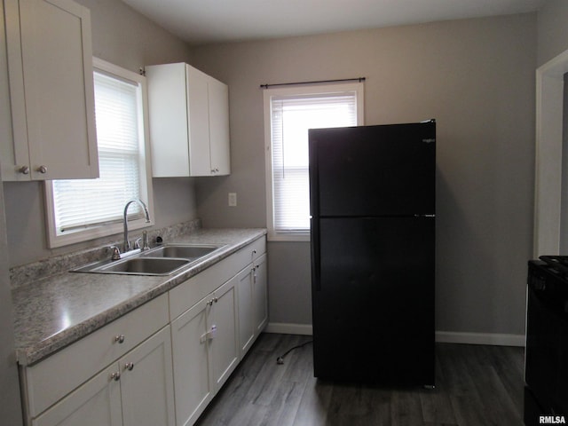 kitchen with white cabinetry, dark hardwood / wood-style floors, sink, and black fridge