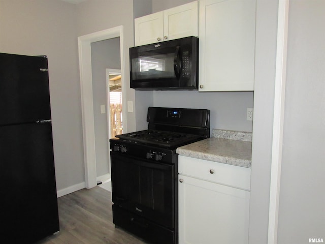 kitchen featuring white cabinets, black appliances, and wood-type flooring