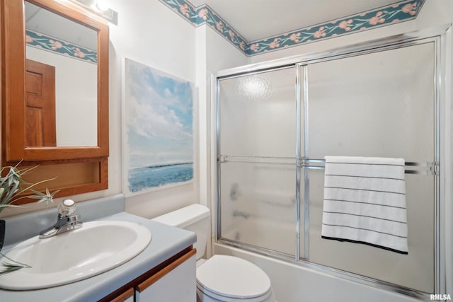 full bathroom featuring toilet, combined bath / shower with glass door, and vanity