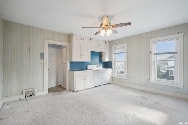 kitchen featuring white cabinets, ceiling fan, and light carpet