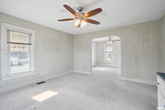 spare room featuring ceiling fan, plenty of natural light, and light carpet