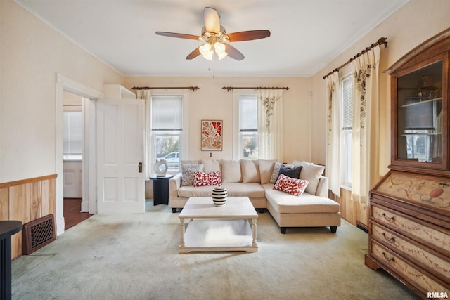 living room featuring carpet flooring, wood walls, crown molding, and ceiling fan