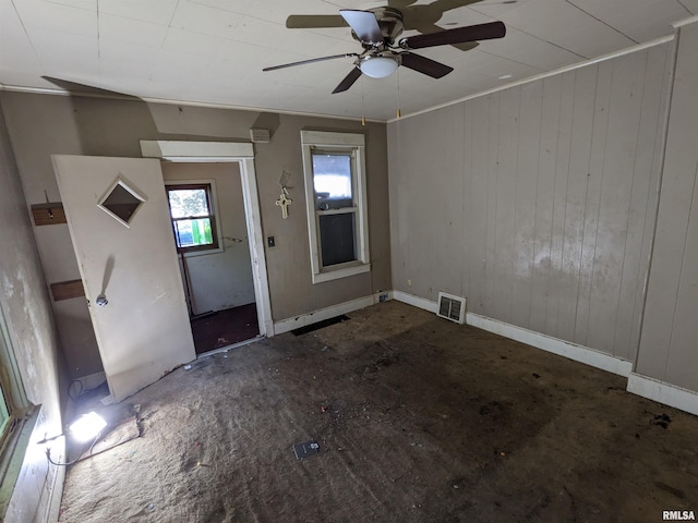 foyer entrance featuring ceiling fan, crown molding, and wooden walls