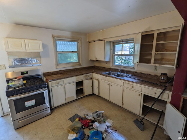 kitchen with gas range, white cabinetry, and sink