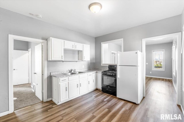 kitchen with white cabinets, black gas range, light hardwood / wood-style floors, white fridge, and sink