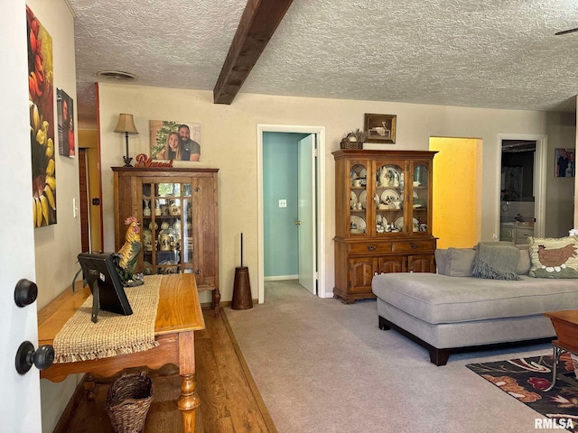 carpeted living room featuring beamed ceiling and a textured ceiling