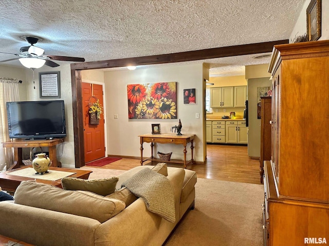 living room featuring light hardwood / wood-style floors, a textured ceiling, beam ceiling, and ceiling fan