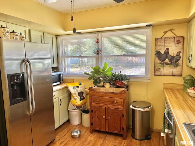 kitchen with stainless steel appliances, wood counters, light wood-type flooring, white cabinetry, and a textured ceiling