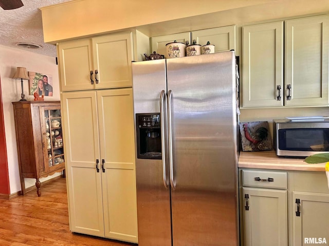 kitchen with a textured ceiling, appliances with stainless steel finishes, and light hardwood / wood-style flooring