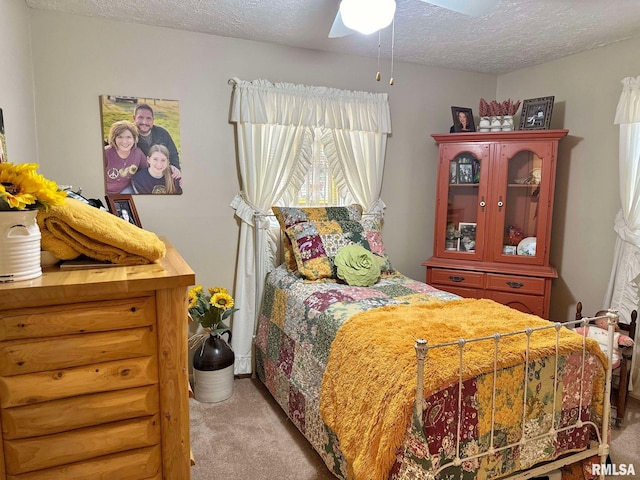 carpeted bedroom featuring ceiling fan and a textured ceiling