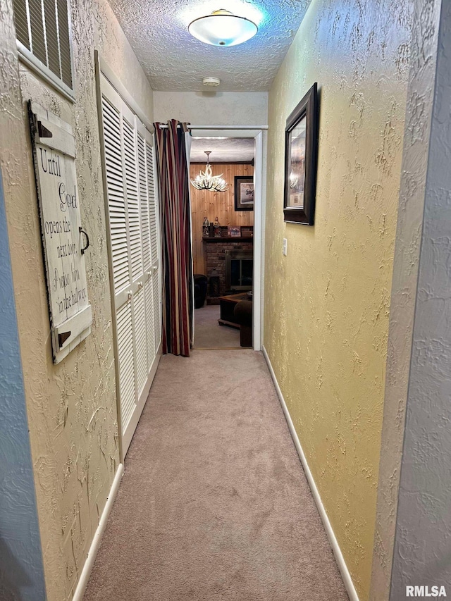 hall featuring a chandelier, a textured ceiling, and carpet flooring