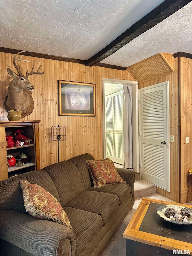 carpeted living room featuring a textured ceiling, beamed ceiling, wooden walls, and ornamental molding