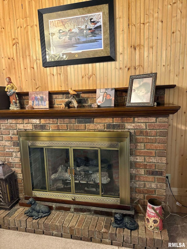 interior details featuring carpet, a brick fireplace, and wooden walls