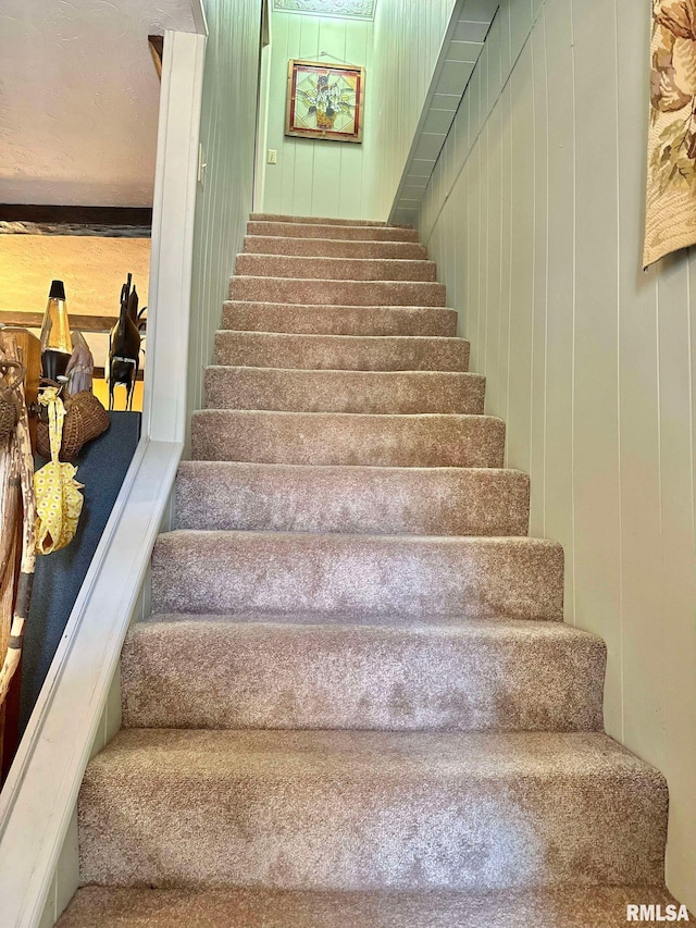 staircase featuring wooden walls