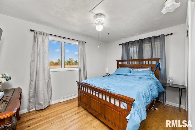 bedroom with a baseboard radiator, light hardwood / wood-style floors, and ceiling fan