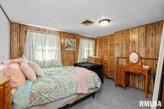 carpeted bedroom featuring a closet and wood walls