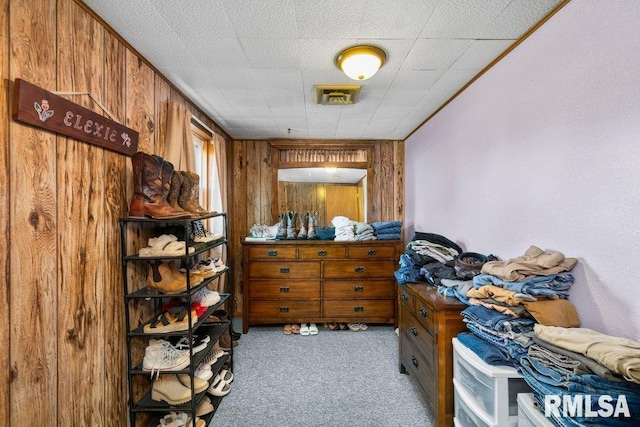 bedroom with light carpet and wood walls