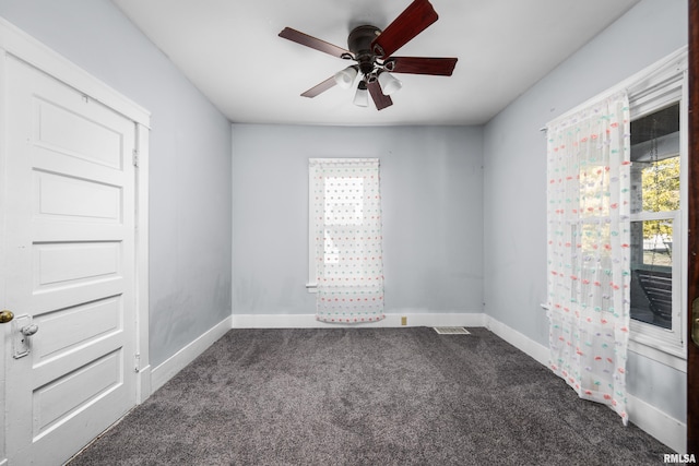 spare room with dark carpet and ceiling fan