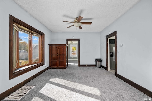 carpeted empty room featuring a textured ceiling and ceiling fan