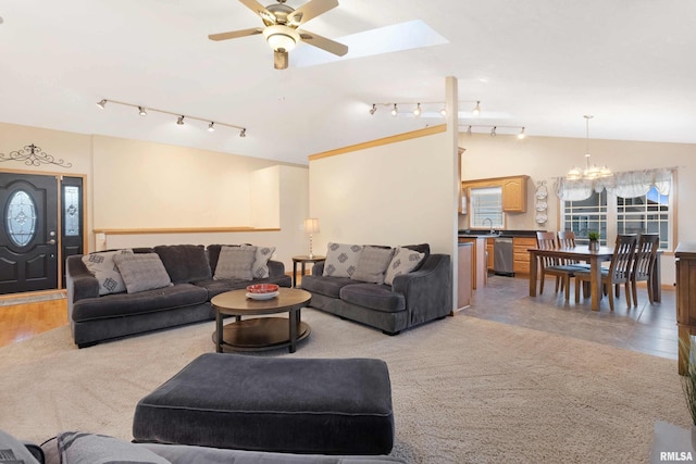 living room with vaulted ceiling with skylight, ceiling fan with notable chandelier, sink, and light wood-type flooring