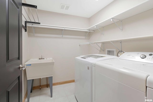 clothes washing area featuring washer and clothes dryer, sink, and light tile patterned flooring