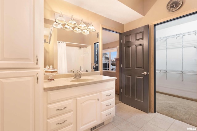 bathroom with walk in shower, vanity, and tile patterned flooring