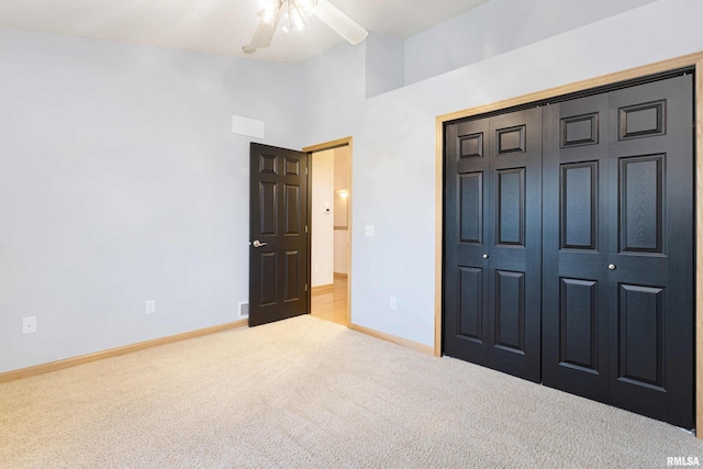 unfurnished bedroom with ceiling fan, a high ceiling, light colored carpet, and a closet