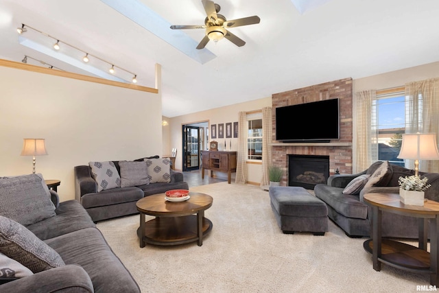 living room featuring a fireplace, track lighting, light carpet, vaulted ceiling, and ceiling fan