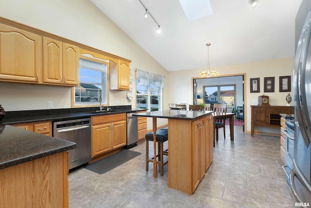 kitchen with a wealth of natural light, appliances with stainless steel finishes, lofted ceiling with skylight, and a center island