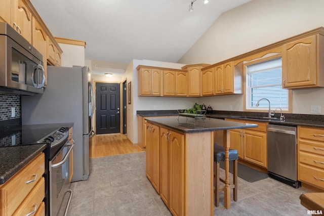 kitchen featuring appliances with stainless steel finishes, sink, a kitchen breakfast bar, lofted ceiling, and a center island