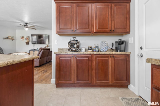 kitchen featuring light stone counters, light hardwood / wood-style floors, and ceiling fan