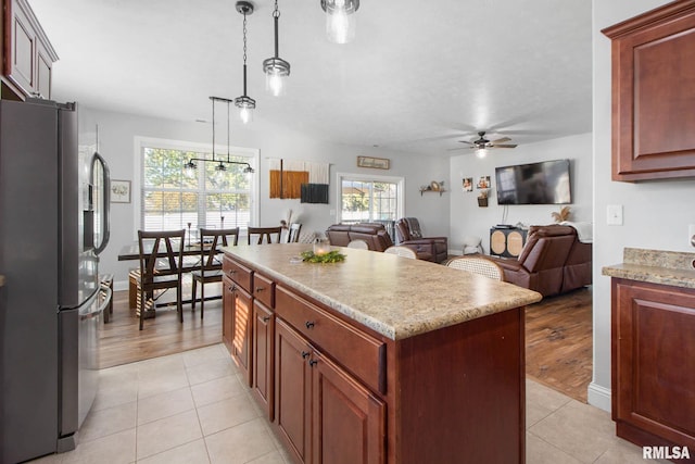 kitchen with stainless steel fridge, ceiling fan, pendant lighting, light hardwood / wood-style floors, and a center island