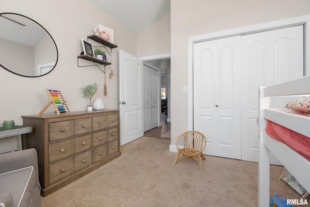 bedroom with lofted ceiling, light carpet, and a closet