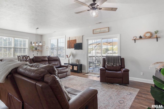 living room featuring ceiling fan, a textured ceiling, dark hardwood / wood-style flooring, and plenty of natural light