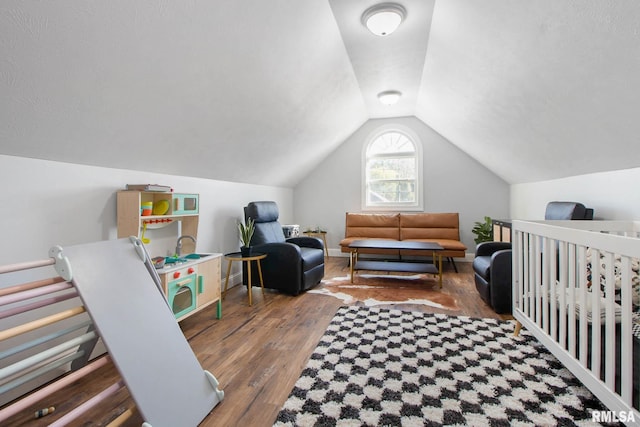 bedroom featuring lofted ceiling, a crib, and dark hardwood / wood-style flooring