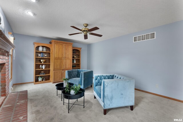 living area with a fireplace, light carpet, a textured ceiling, and ceiling fan