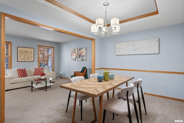 carpeted dining area with a textured ceiling, crown molding, and a notable chandelier