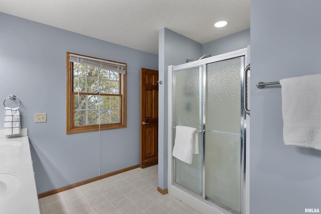 bathroom with vanity, a textured ceiling, and walk in shower