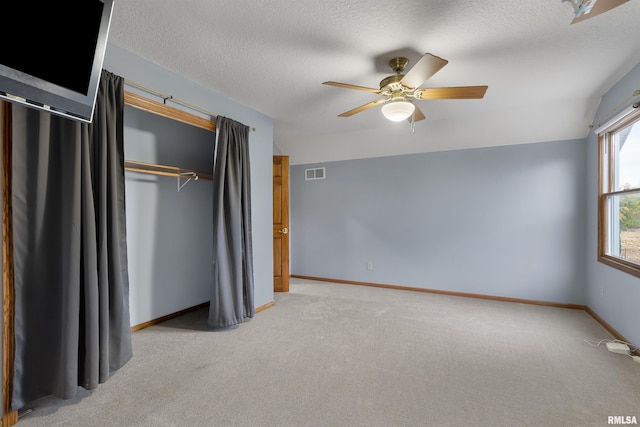 unfurnished bedroom with ceiling fan, a closet, light carpet, and vaulted ceiling