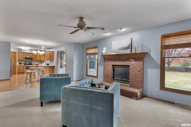 living room with light carpet, a textured ceiling, ceiling fan with notable chandelier, and a brick fireplace