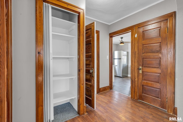 hall with ornamental molding, a textured ceiling, and hardwood / wood-style flooring