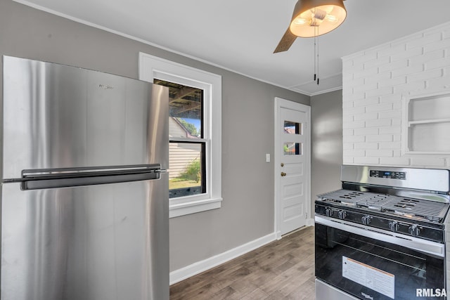 kitchen with appliances with stainless steel finishes, ornamental molding, and wood-type flooring