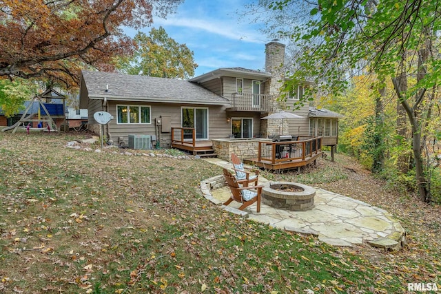 back of house featuring a wooden deck, a fire pit, a patio, and a yard