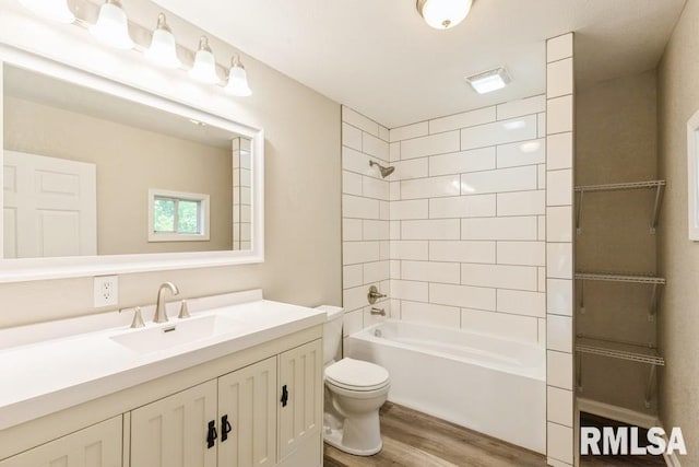 full bathroom with hardwood / wood-style flooring, vanity, toilet, and tiled shower / bath