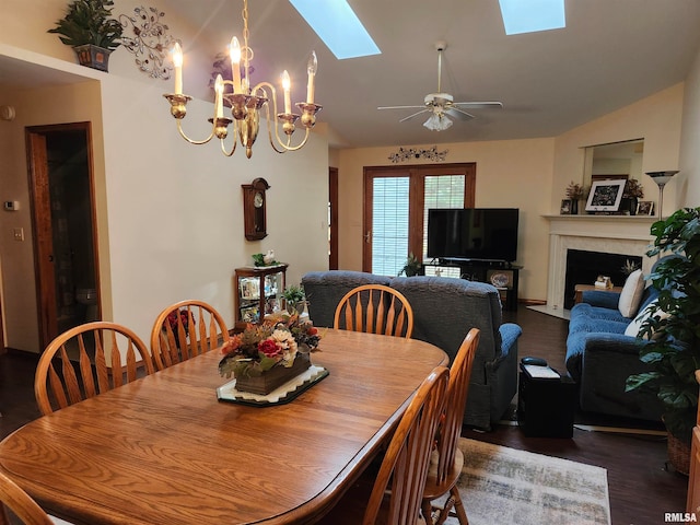 dining space featuring ceiling fan with notable chandelier, lofted ceiling with skylight, and dark hardwood / wood-style floors