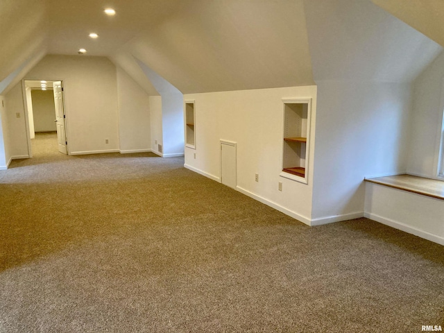 additional living space with built in shelves, carpet floors, and vaulted ceiling