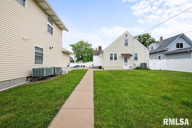 back of house with central air condition unit and a lawn