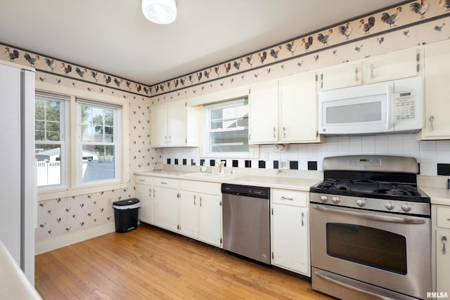 kitchen featuring decorative backsplash, stainless steel appliances, sink, light wood-type flooring, and white cabinetry