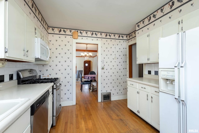 kitchen with an inviting chandelier, light hardwood / wood-style flooring, white cabinets, and stainless steel appliances