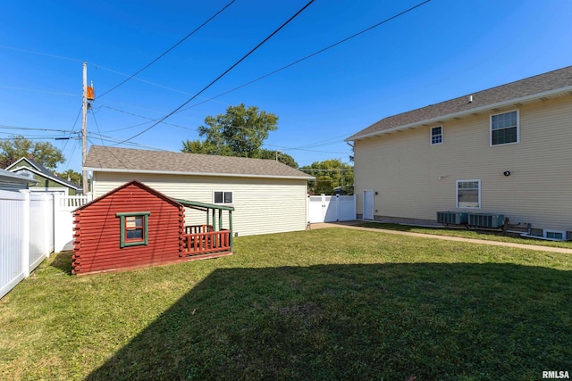 back of house with central air condition unit, a deck, and a lawn